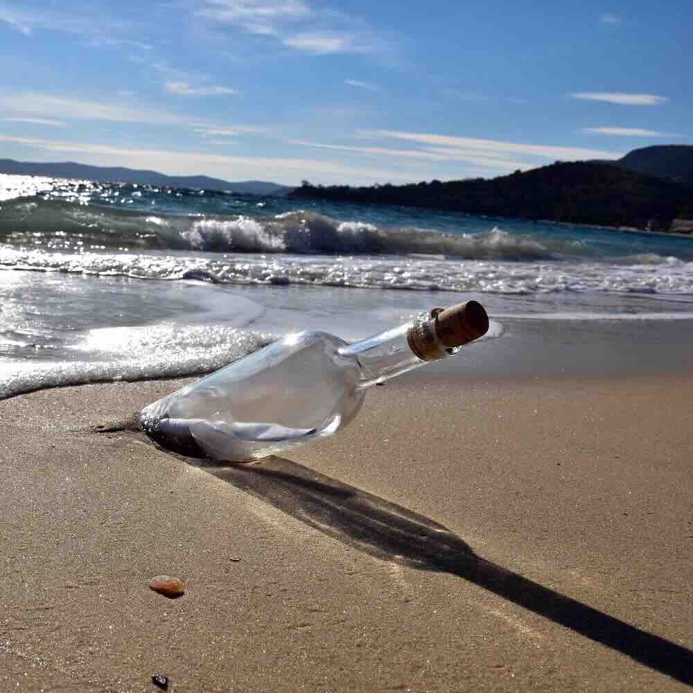 Message in a bottle sticking out of the sand on a sunny beach. Women’s drop-in circles, sharing circles, workshops, retreats on Vancouver Island. Heart~Soul Path.